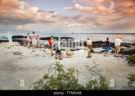 Des îles Galapagos, en Équateur, un groupe de personnes flâner sur la plage et regarder le coucher du soleil de l'île Fernandina Banque D'Images