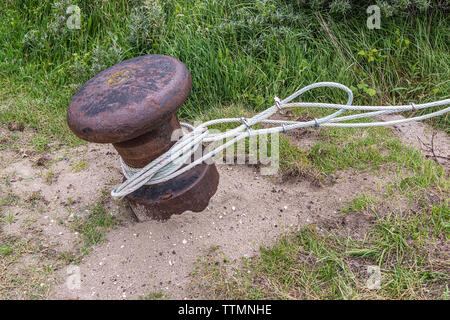 Câble corde enroulée autour d'un bollard rouillée dans les dunes Banque D'Images