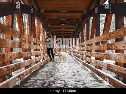 Teenage girl with dog sur un pont couvert de neige. Banque D'Images