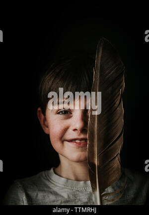 Portrait de jeune garçon tenant un grand feather plus de la moitié de son visage. Banque D'Images