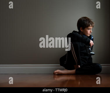 Preteen boy sitting on floor avec contrôleur de jeu vidéo dans la main. Banque D'Images