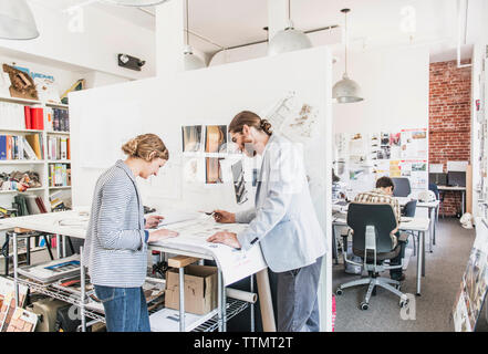 Colleagues discussing blueprints in office Banque D'Images