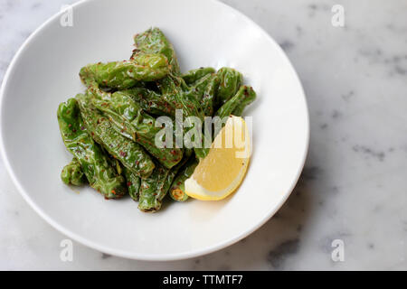 High angle view of fried green chili peppers avec tranche de citron dans un bol sur la table Banque D'Images