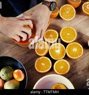 Vue directement au-dessus des mains Presser les oranges Banque D'Images