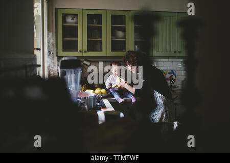 Les jeunes baby girl sitting on gramma's compteur de cuisine manger jam Banque D'Images