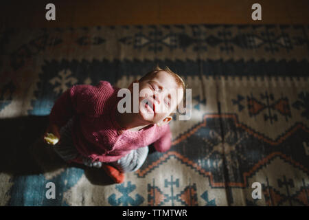 Une fille de bébé assis sur un tapis à la vers le haut avec les yeux fermés Banque D'Images