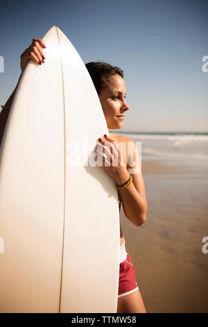 Young woman standing with surfboard on beach Banque D'Images