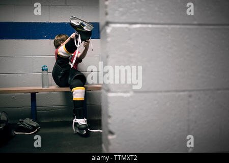 Boy putting sur patins de hockey sur glace Banque D'Images