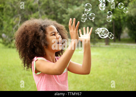 Petite fille afro attraper des bulles de savon Banque D'Images