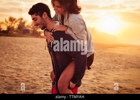 Man giving piggyback ride à sa petite amie sur la plage Banque D'Images