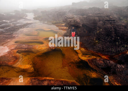 Portrait de femme assise sur un rocher près du lac par temps brumeux Banque D'Images