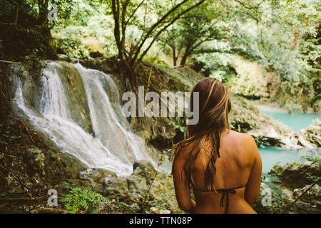 Young woman wearing bikini top while looking at view in forest Banque D'Images