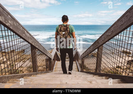 Vue arrière du sac à dos de randonneur avec marches en bois sur pied à la plage Banque D'Images