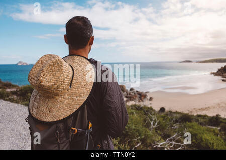 Vue arrière du randonneur avec chapeau de paille et sac à dos à la recherche en mer contre le ciel à Wilsons Promontory National Park Banque D'Images