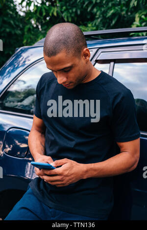 Young man using mobile phone while standing location Banque D'Images