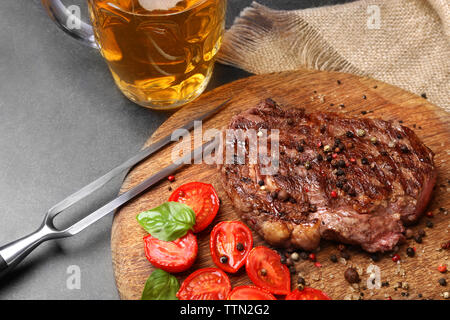 Steak savoureux avec des tomates et de la bière on cutting board Banque D'Images