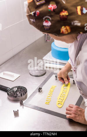 Vue de côté avec la pâte de coupe féminine Baker sur l'emporte-pièces cuisine in laboratory Banque D'Images