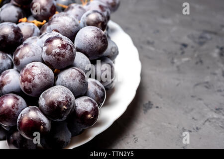 Tas de raisins noirs sur une plaque blanche Banque D'Images