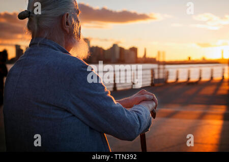 Senior man sitting on promenade au coucher du soleil Banque D'Images