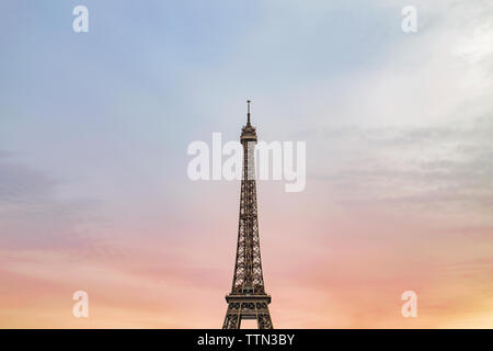 Low angle view of Tour Eiffel contre ciel nuageux pendant le coucher du soleil Banque D'Images