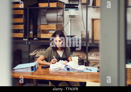 Propriétaire de sexe féminin à l'analyse des documents at table in coffee shop Banque D'Images