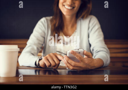 Portrait of smiling woman using mobile phone at cafe Banque D'Images