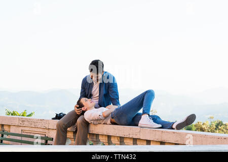 Couple romantique au mur de soutènement de terrasse contre ciel clair Banque D'Images