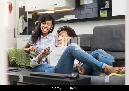 Heureux de parler d'amis tout en appréciant la musique via smart phone at home Banque D'Images