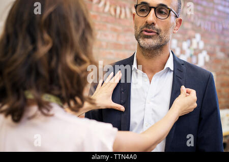 Vue arrière du créateur de mode de prise de mesure sur le businessman en atelier Banque D'Images