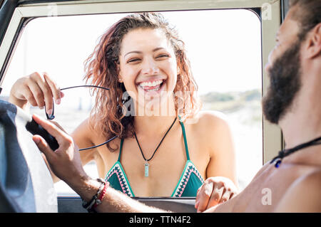 Cheerful Woman talking to ami masculin assis en véhicule hors route Banque D'Images