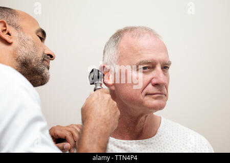 Médecin à l'aide d'un otoscope lors de l'examen de l'oreille du patient à l'hôpital Banque D'Images