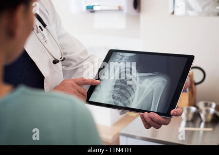 Portrait du docteur montrant x-ray image sur tablet computer to patient in hospital Banque D'Images