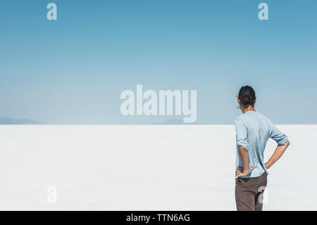 Vue arrière de l'homme debout à salt flat against clear blue sky Banque D'Images