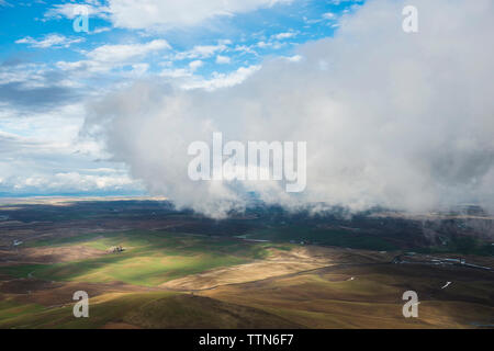 Portrait de collines et de terres agricoles contre ciel nuageux Banque D'Images