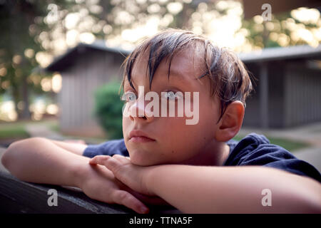 Close-up of boy à la route tout en se penchant sur un banc du park Banque D'Images