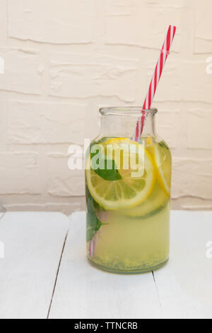 Fat Burning Sassy avec de l'eau, la menthe citron, le gingembre et le concombre dans un pot sur la table en bois blanc Banque D'Images