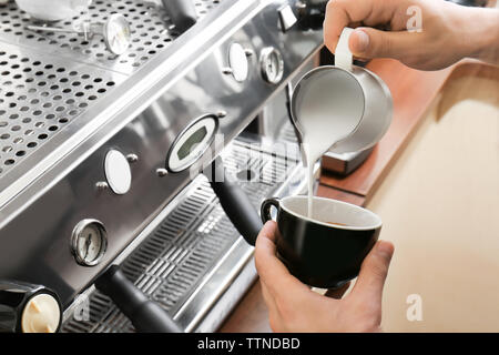 L'homme s'appuyant sur le café avec de la mousse de lait Banque D'Images