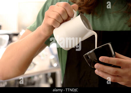 Verser la crème dans le café de l'homme Banque D'Images