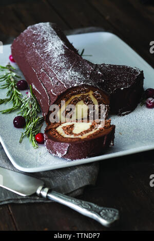 Vue en grand angle de la bûche de yules servie avec du romarin dans une assiette sur la table à la maison pendant Noël Banque D'Images