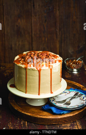 Vue en grand angle du gâteau au caramel sur le cakestan contre un mur en bois à la maison Banque D'Images