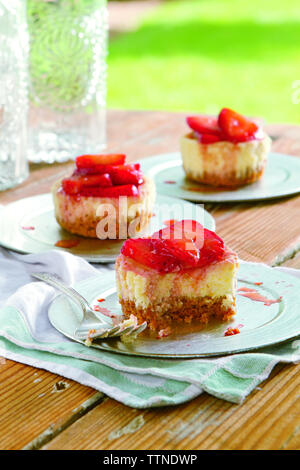 Cheesecakes garnies de fraises servies dans des assiettes sur une table en bois à la maison Banque D'Images