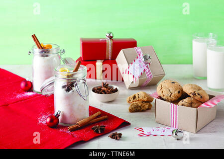 Biscuits aux pépites de chocolat avec du lait et des épices sur une table en bois contre le mur à la maison pendant Noël Banque D'Images