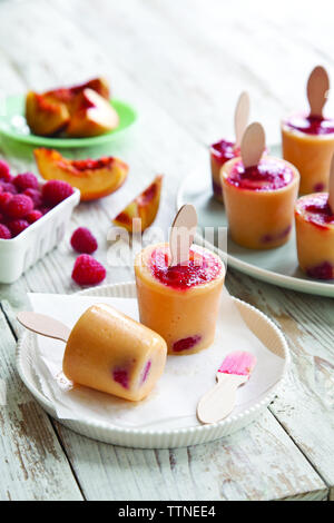 Gros plan de pop-sicles de framboise et de pêche sur une table à la maison Banque D'Images