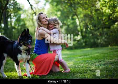 Mère embrassant pleurer la fille par chien sur terrain Banque D'Images