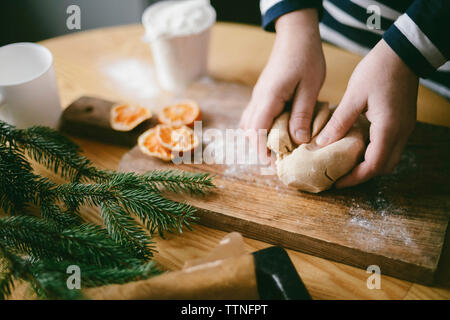 Portrait de femme mains pétrissant la pâte sur une planche à découper dans la cuisine à la maison Banque D'Images