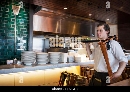 Confiant waiter holding lave tout en marchant en cuisine commerciale Banque D'Images