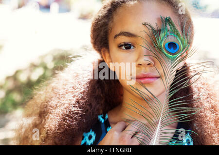Close-up portrait of girl holding peacock feather Banque D'Images