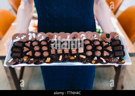 Midsection of woman holding divers chocolats dans le bac par store Banque D'Images