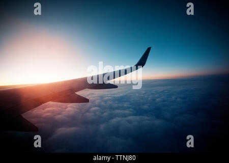 Image recadrée de vol d'un avion au ciel nuageux pendant le coucher du soleil Banque D'Images