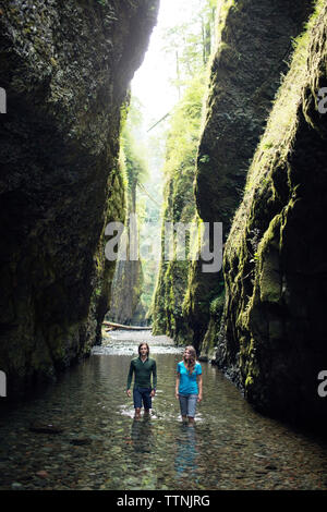 Couple en train de marcher dans le ruisseau au milieu des rochers Banque D'Images